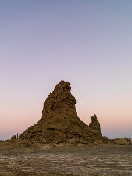 A full moon rises beside a towering limestone chimney at dusk, Afar depression, Lake Abbe, Djibouti