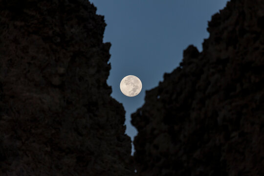 A full moon glows between two dark limestone chimney silhouettes, Afar depression, Lake Abbe, Djibouti