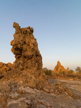 A full moon hovers above a solitary limestone chimney rock formation, Afar depression, Lake Abbe, Djibouti