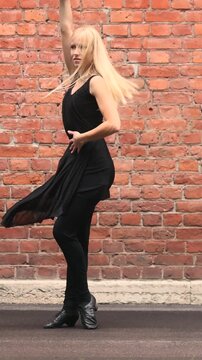 Ballroom dancer moves through Latin steps against brick wall