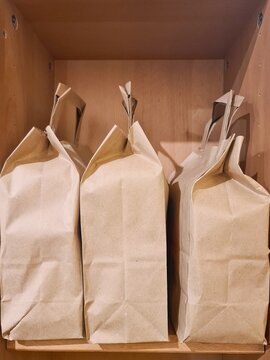 Brown paper bags storing goods on a wooden shelf
