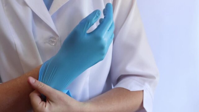Medical worker puts on blue nitrile gloves, close-up of hands of nurse or doctor, first aid, medical clothing. Putting on blue disposable gloves. Protection against viruses, bacteria and chemicals
