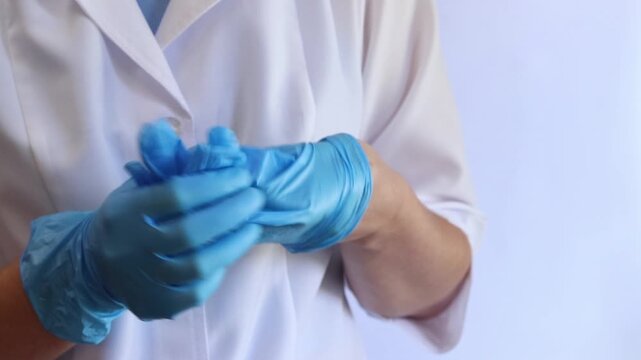 Medical worker puts on blue nitrile gloves, close-up of hands of nurse or doctor, first aid, medical clothing. Putting on blue disposable gloves. Protection against viruses, bacteria and chemicals