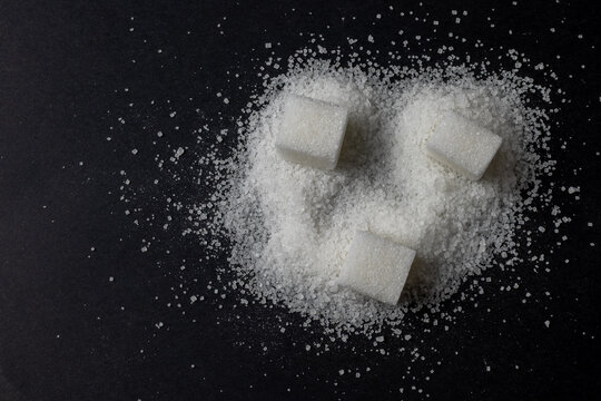 White Sugar Cubes And Granulated Sugar On Dark Background