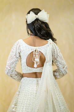 Side view profile shot of a young Indian bride wearing a silver and green emerald necklace set with matching long drop earrings.