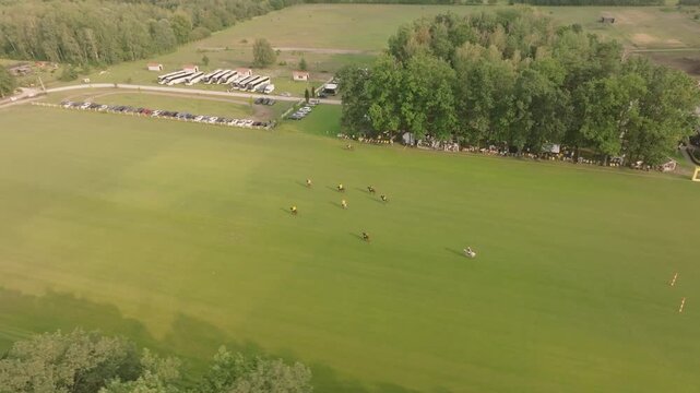 Aerial view of polo players competing in a match on a green field