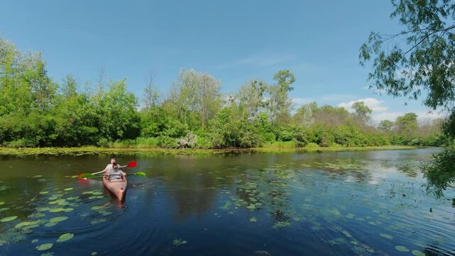 Mature couple kayaking together on calm river water in summer forest environment promoting active lifestyle