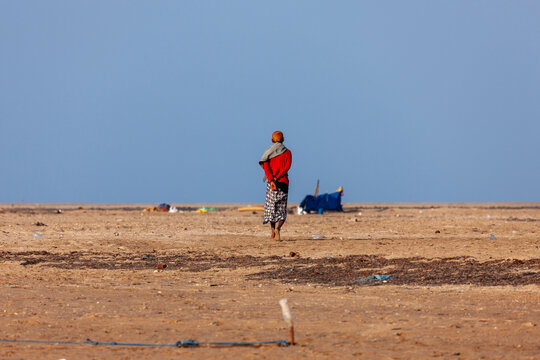 An afar  man in a red shirt walks across a barren coastal plain, Obock Region, Gorodia, Djibouti