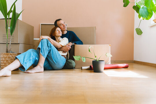 A mature caucasian couple spends time together on the floor surrounded by cardboard moving boxes. Happy family relocation and new property ownership concept.