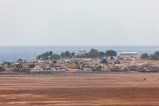 White buildings of a coastal town line the shore beyond a dried mudflat, Obock Region, Obock, Djibouti