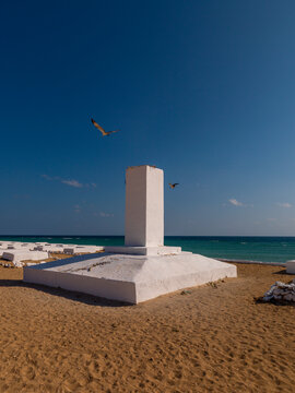 Two birds fly above a memorial obelisk in a French colonial marine cemetery, Obock Region, Obock, Djibouti