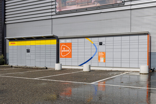 Den Bosch, Netherlands - 16 September 2026: Automated parcel locker machine featuring compartments from major courier services DHL, PostNL, GLS, and FedEx stationed outside a commercial building.