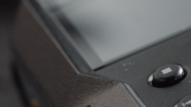 Macro close up of a black electronic control panel featuring a prominent red button and blue switches surrounded by smaller control buttons.