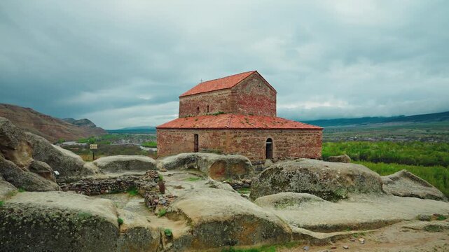The red roofed Uplistsulis brick basilica stands on the rock above the green river valley of Shida Kartli.
