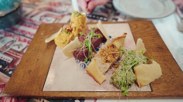 A platter of colourful Georgian pkhali with walnut, spinach and beetroot is served with crisp crackers on a wooden board.