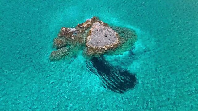 Firiplaka Beach features a pale volcanic rock formation surrounded by clear turquoise water on Milos, South Aegean, Greece, Europe, static aerial shot