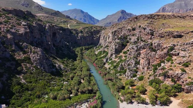 Megalopotamos River cuts through Preveli Gorge between Kouroupa and Xiro Oros, with rugged limestone ridges and mountain peaks in Rethymno, Crete, Greece, drone pullback