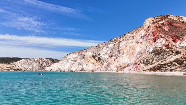 Firiplaka Beach lies beneath strongly colored volcanic cliffs near Provatas, Milos Municipality, South Aegean, Greece, with pale shoreline and rugged pyroclastic outcrops, drone forward flyover