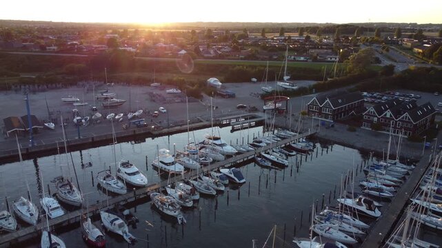Sailboats and docks fill Ega Marina near Aarhus, Denmark in warm evening light, aerial
