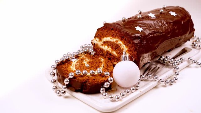 Chocolate Yule log Christmas cake with silver decorations on white platter