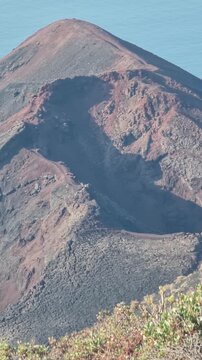 Perspectiva vertical de las paredes del cr&aacute;ter y la cumbre de tonos rojizos y oscuros del volc&aacute;n Tenegu&iacute;a en Fuencaliente, La Palma.