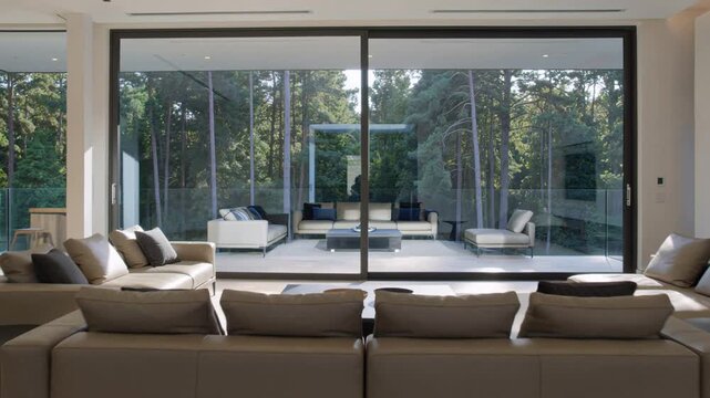 Modern interior of a luxury living room with high ceilings and large panoramic windows overlooking a pine forest