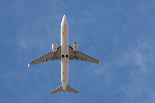 Passenger plane seen from below against a clear blue sky