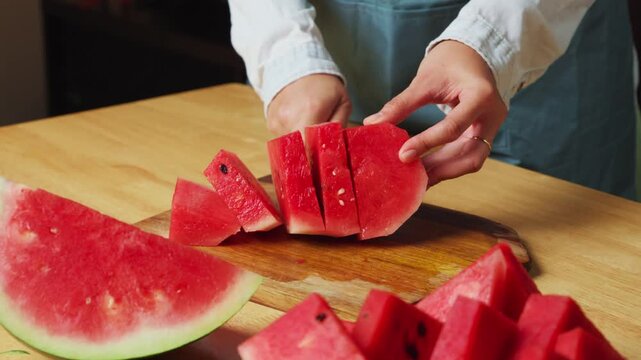 Cutting fresh watermelon into slices on a wooden cutting board