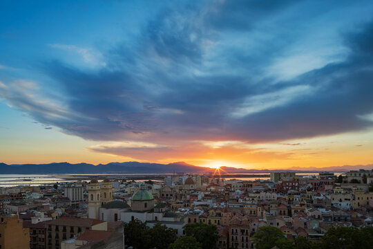 Cagliari city skyline at Sunset with glowing sun and clouds