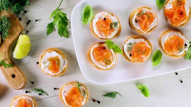 Smoked salmon canapes with cream cheese and dill on white plate top view