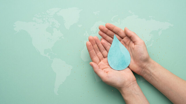 Hands holding water droplet symbolizing global health and immunization efforts on world polio day with background representing clean hands cradle translucent against world map