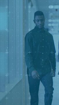 Vertical video: Man emerging from dark walking office toward meeting, blue overlay tracking laptop