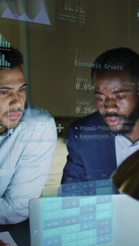 Vertical video: Two men sitting at laptop, overlay appearing and marking financial data to review