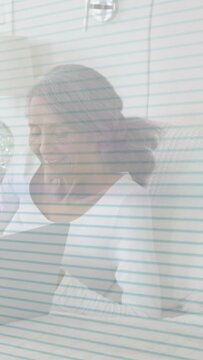 Vertical video: Woman sitting bed laughing at offscreen cue for health lined overlay crossing frame