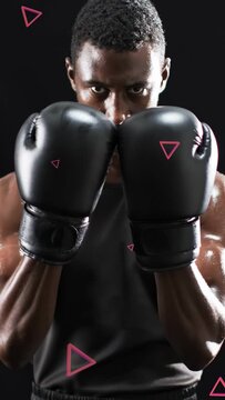Vertical video: Boxer holding guard lifting gaze as pink triangles overlaying gloves for sports ad