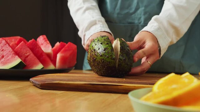 Person cutting a fresh soursop fruit in half on a wooden cutting board