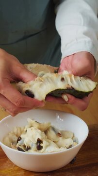 Fresh soursop pulp being separated from the peel by hand