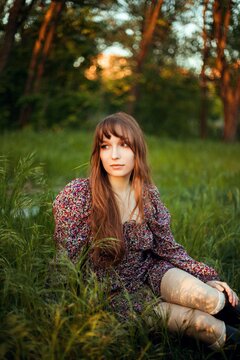 Young woman sitting in grass during sunset in a park