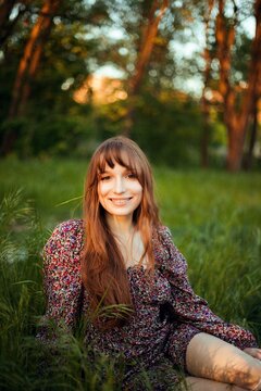 Young woman sitting in grass during sunset in a park