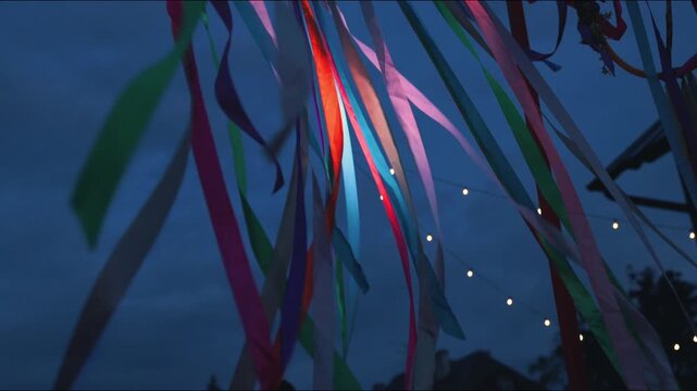 Colorful ribbons sway gently in the evening breeze against a twilight sky, creating a vibrant display reminiscent of a Woodstock-style celebration atmosphere