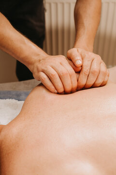 closeup view of hands pressing and kneading bare back during spa massage, warm lighting and calm atmosphere