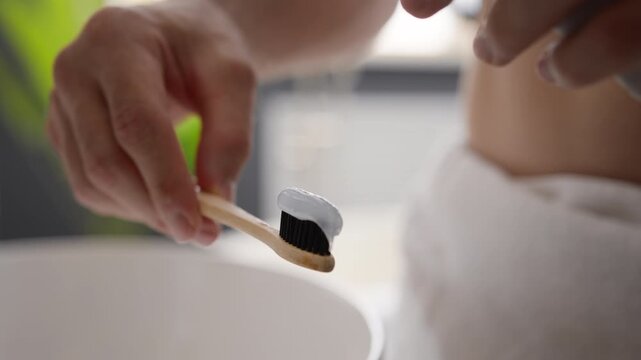 Close up male hands squeezing whitening toothpaste on bamboo toothbrush unrecognizable Caucasian man brushing teeth doing morning oral tooth hygiene dental care cleaning routine fresh breath indoors
