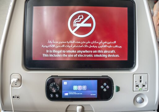 Screen with display smoking ban in Arabic and English on backrest in aircraft, Emirates airline, interior, Dubai, United Arab Emirates