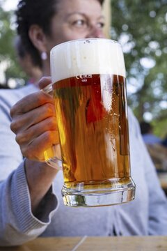 Woman (50-55) with a glass of beer in a beer garden, Prague, Bohemia, Czech Republic