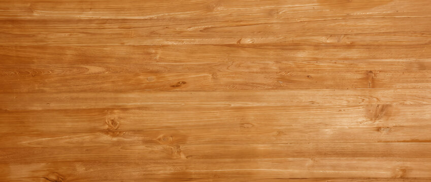 Varnished wood floor texture background showing glossy honey brown teak plank boards with natural knots for interior design use