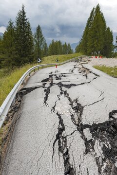 Road damage, broken road with cracks in the road surface, broken carriageway of a mountain road, Belluno, Italy