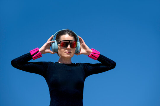 Woman in sportswear with Headphones and Sunglasses and wrist weights