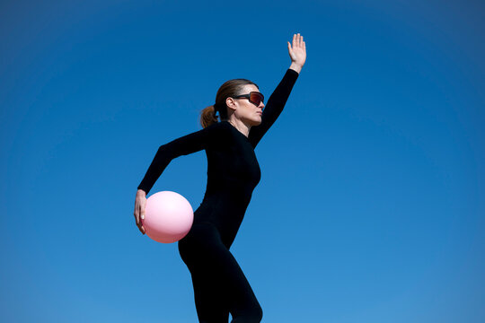 Woman in Black Jumpsuit Balancing a Pink Exercise Ball
