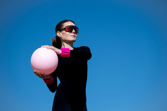 Woman in Black Sportswear Holding a Pink Pilates Ball and Wearing Wrist Weights