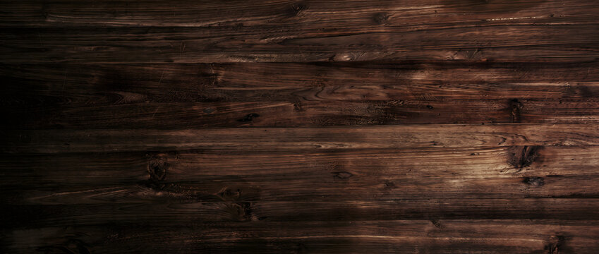 Dramatic dark wood wall texture background showing rich brown timber plank boards with angled light for cinematic design use